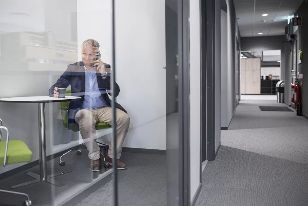 celular corporativo homem conversando sala